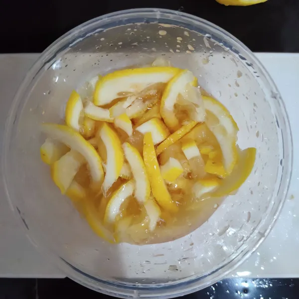 Iris tipis-tipis lemon, simpan di wadah bersih kemudian beri madu, tutup wadah, simpan selama 1 malam di chiller.