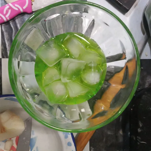 Tuang sirup melon ke dalam gelas lalu beri es batu.