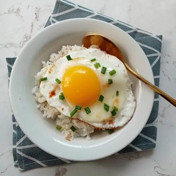 Letakkan telur diatas nasi panas. Beri taburan daun bawang diatasnya dan ciprati telur dengan minyak wijen secukupnya. Sajikan.