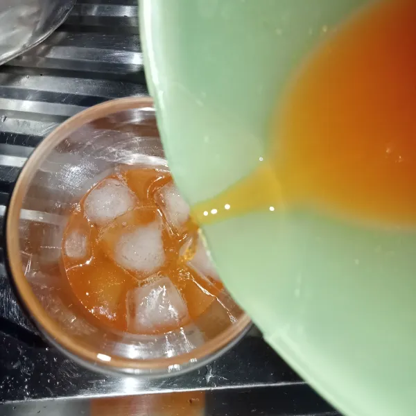 Dalam gelas masukkan es batu. 
Tuang perasan jeruk.