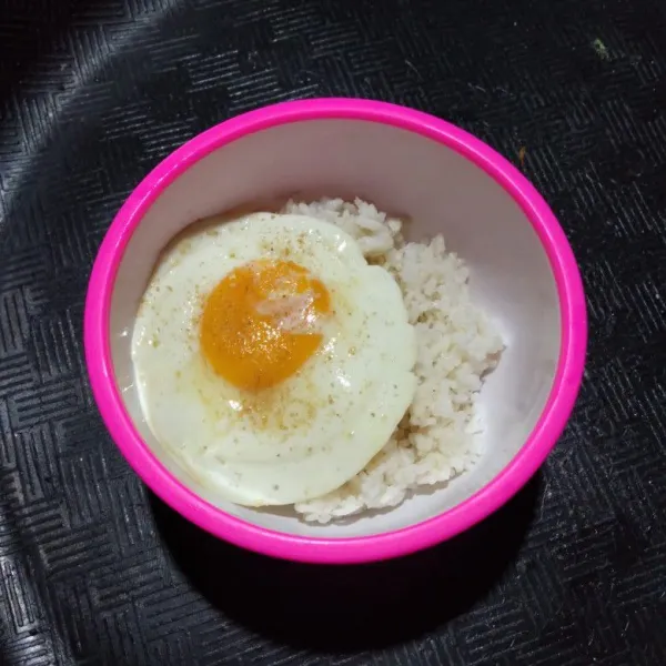 Letakkan telur ceplok di atas nasi, lalu siram dengan minyak wijen dan kecap asin.