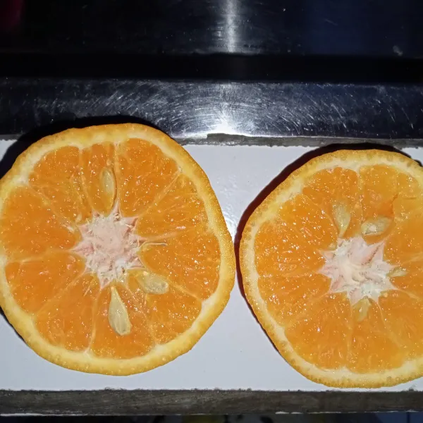 Potong jeruk menjadi dua.