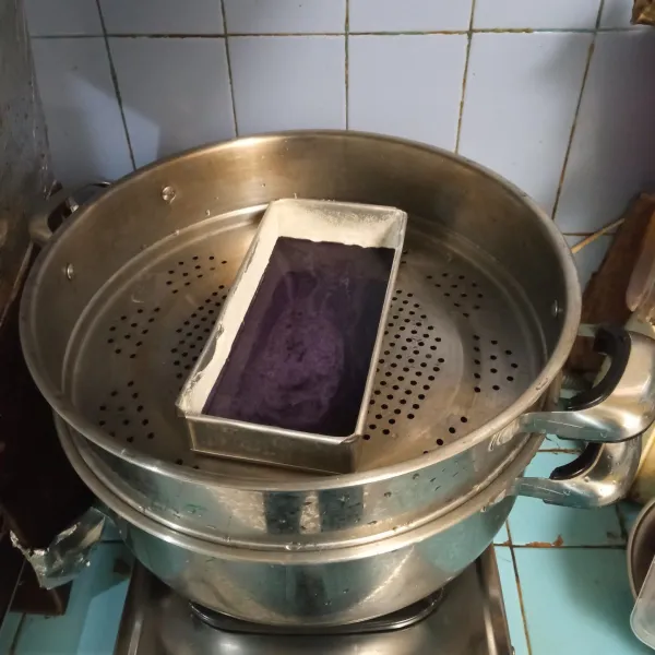 Panaskan panci kukusan, masukkan satu adonan ungu ke dalam loyang yang sudah dioles margarin dan ditaburi tepung terigu. Kukus selama 5 menit.