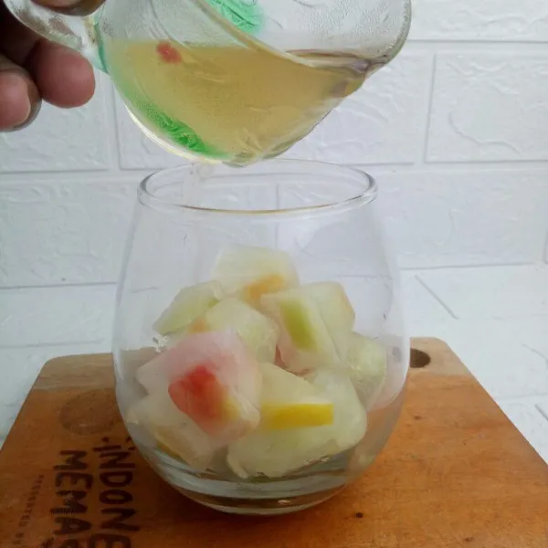 Setelah buah beku lalu masukan ke dalam gelas saji, tuang sisa larutan air gula bergantian dengan air soda dan minuman bersoda sampai 3/4 gelas.