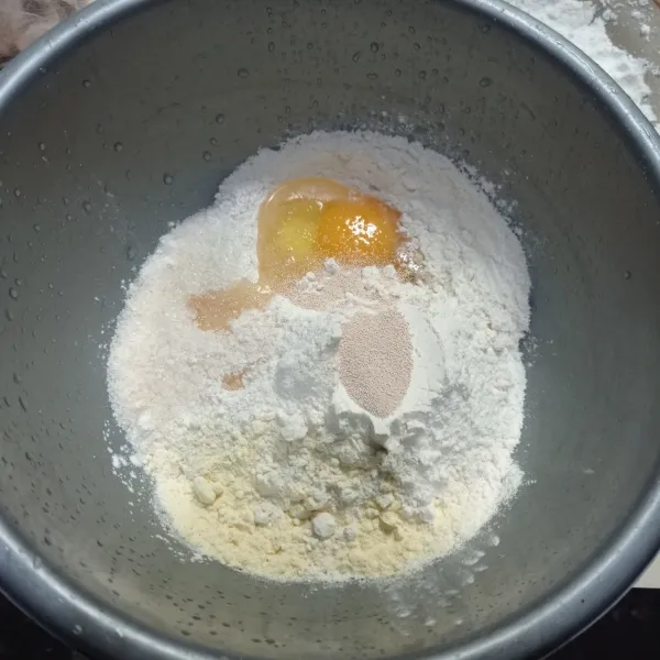 Masukan tepung terigu, gula, telur, ragi instan dan susu bubuk ke dalam wadah.