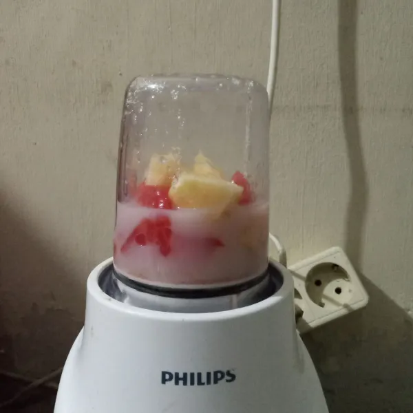 Masukkan potongan buah ke dalam blender, tambahkan gula pasir, air dan susu uht.