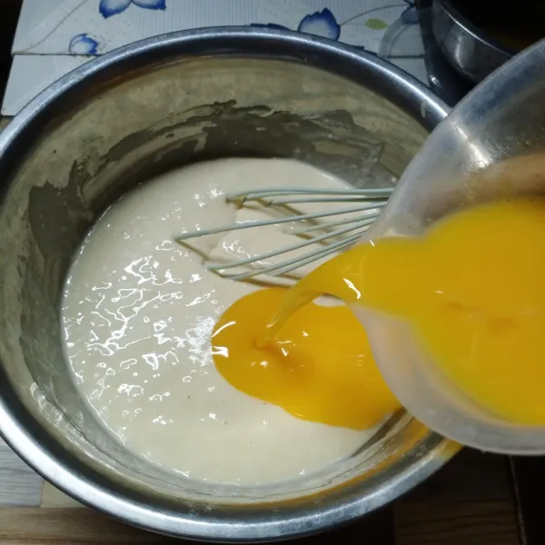 Setelah 30 menit, kocok lepas telur dan gula pasir. Tuang ke adonan terigu sambil diaduk.