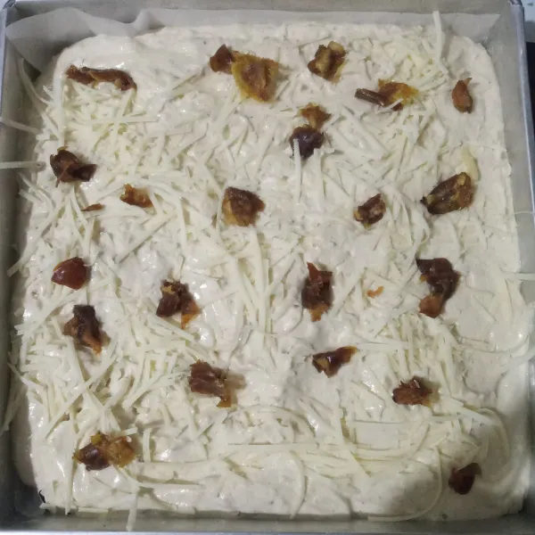 Tuang dalam loyang yang sudah diolesi margarin tipis-tipis, taburi keju parut dan kurma cincang.