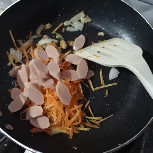 Tumis bawang Bombay, bawang putih sampai layu dengan 3 sdm minyak goreng, lalu masukan wortel dan sosis aduk sampai tercampur rata, masak lagi sampai wortel layu.
