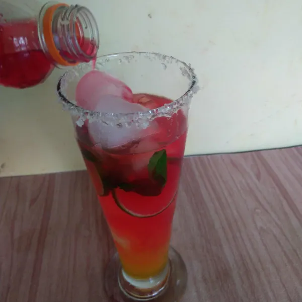 Tuangkan air soda berwarna merah secara perlahan ke dalam gelas agar terbentuk gradasi warna. Sajikan, aduk sebentar sebelum diminum.