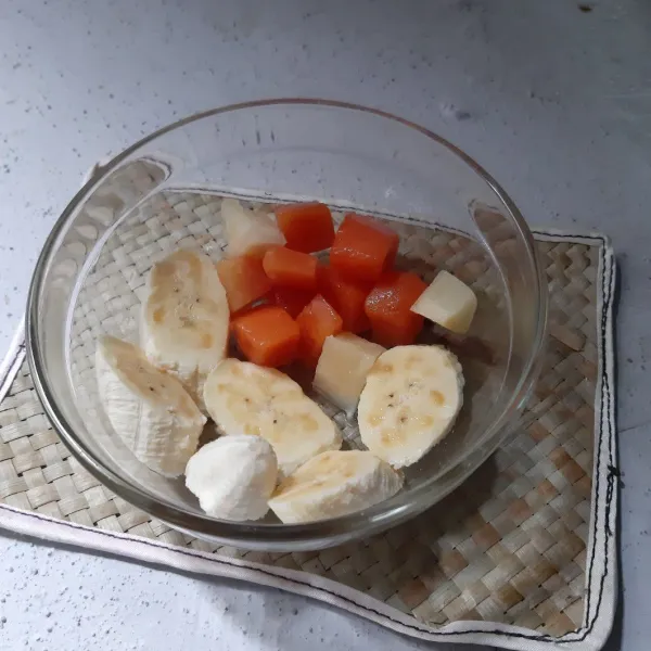 Tata buah kaleng ke dalam mangkuk berisi pisang.