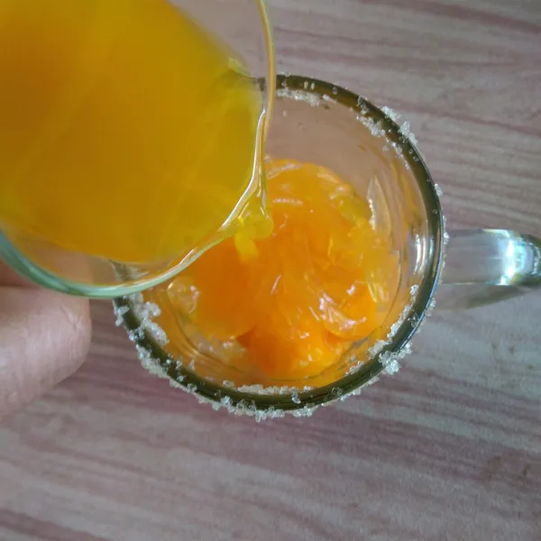 Tuangkan sirup jeruk ke dalam gelas.