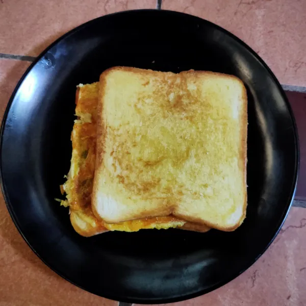 Letakkan telur yang sudah di masak, oles lagi dengan saos sambal lalu tutup dengan 1 lembar roti, potong dan sajikan.