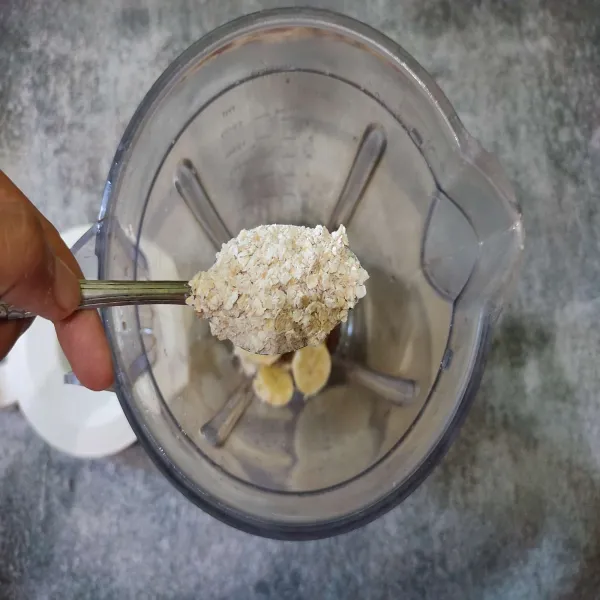 Masukkan es batu dan pisang ke dalam blender lalu beri oatmeal.