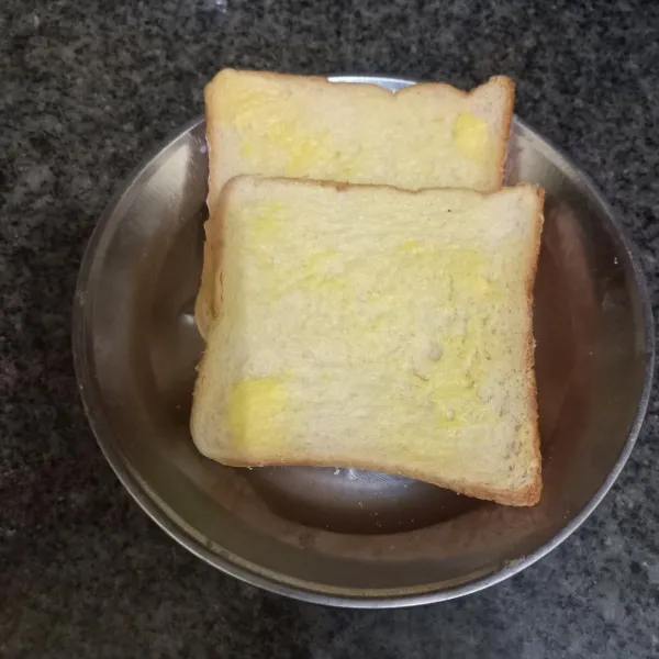 Siapkan roti tawar, oles satu bagian roti dengan margarin.