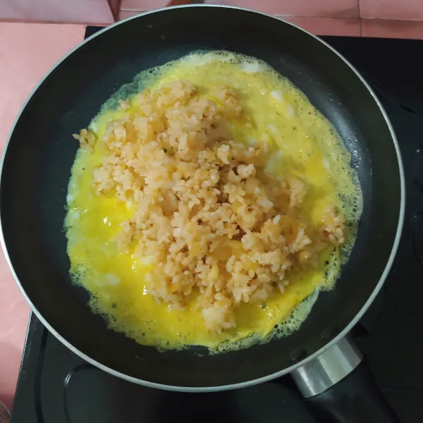 Kocok lepas telur, buat dadar. 
Letakkan nasi di tengah telur lalu lipat kedua sisinya.