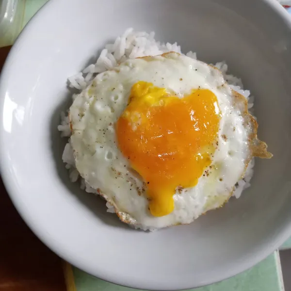 Beri telur ceplok di atas nasi.
