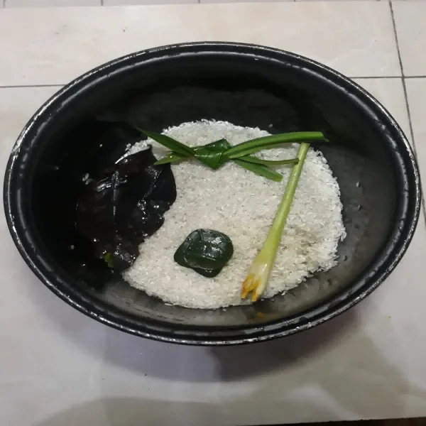 Masukkan serai, daun jeruk, daun salam dan daun pandan ke dalam beras.