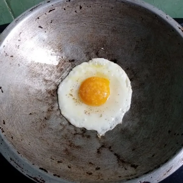 Panaskan minyak, bikin telur ceplok, beri garam dan lada. Bikin telur setengah matang.