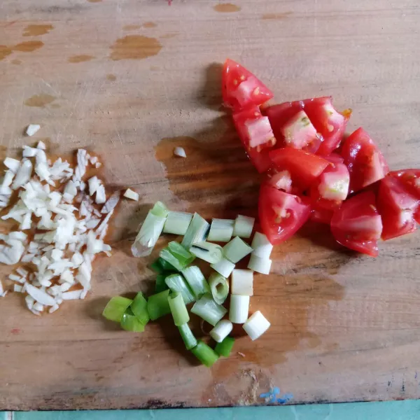 Potong tomat dan daun bawang. Cincang bawang putih.