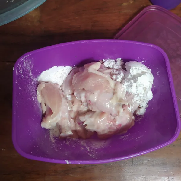 Masukkan tepung maizena dalam wadah yang ada tutupnya. Masukkan ayam yang sudah dimarinasi.