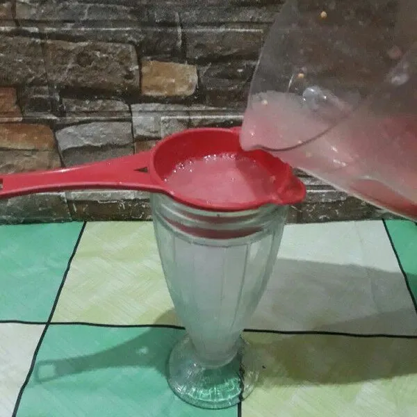 Saring jus jambu ke dalam gelas.