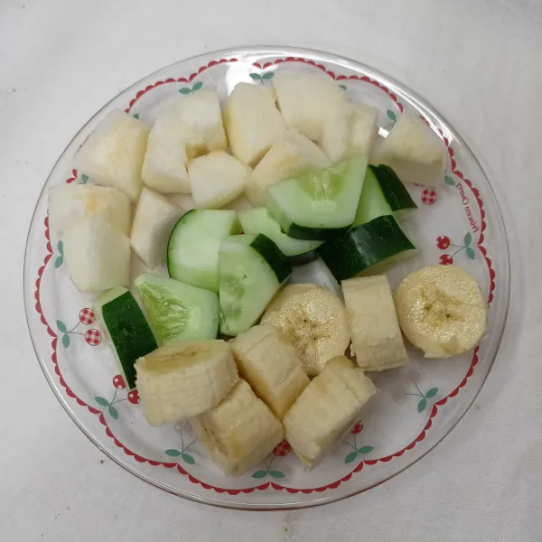 Pertama cuci bersih dan kupas buah pear, mentimun, serta pisang, lalu potong-potong.