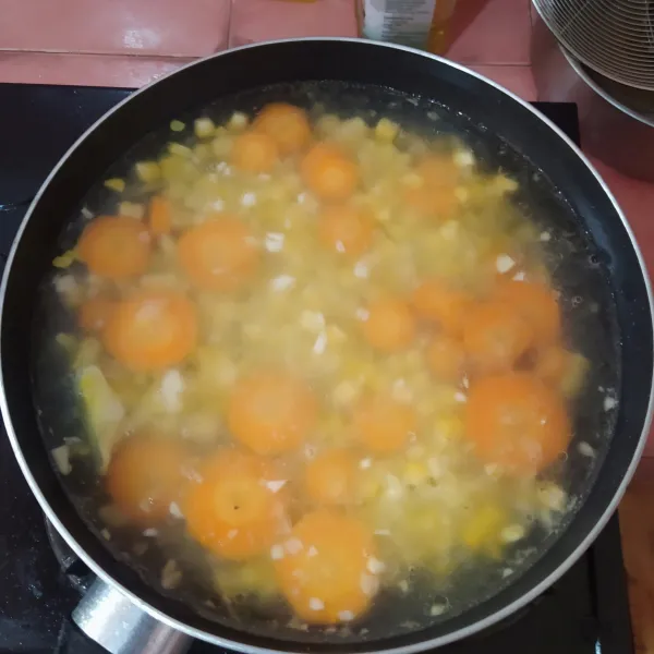 Tuang air setelah mendidih, lalu masukkan jagung manis pipil dan irisan wortel.