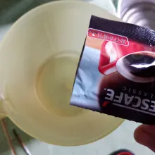 Tuang kopi tanpa ampas dalam cangkir berisi air panas.