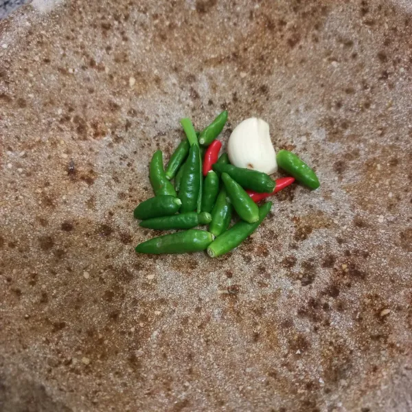 Tumbuk kasar cabe rawit dan bawang putih.