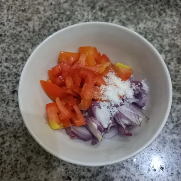 Dalam mangkuk, campur irisan bawang merah, irisan tomat yang telah dibuang bijinya, garam dan gula pasir, aduk rata.