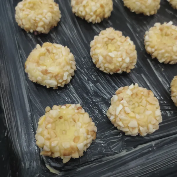 Tata di atas loyang yang sudah di olesi dengan margarin, lalu tekan bagian atas cookies agar terbentuk cekungan.