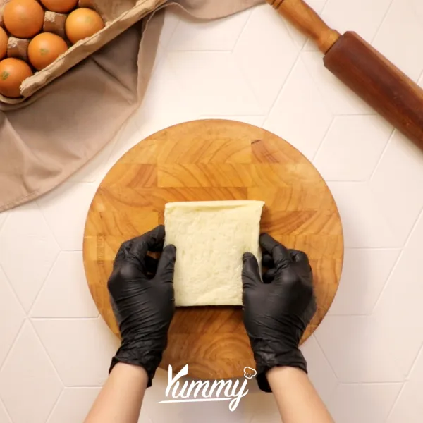 Taruh roti tawar di atas alas, kemudian pipihkan menggunakan rolling pin.