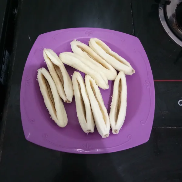 Kupas pisang, lalu belah tengahnya tetapi tidak putus.