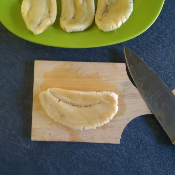 Kupas pisang lalu pipihkan di atas talenan menggunakan pisau.