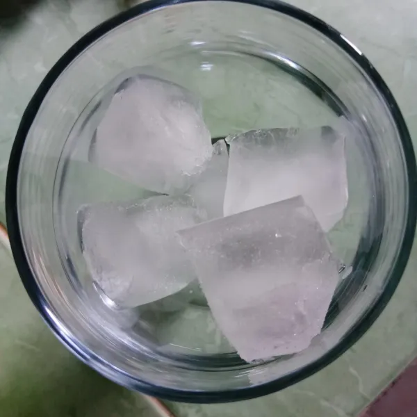 Masukkan es batu ke dalam gelas.