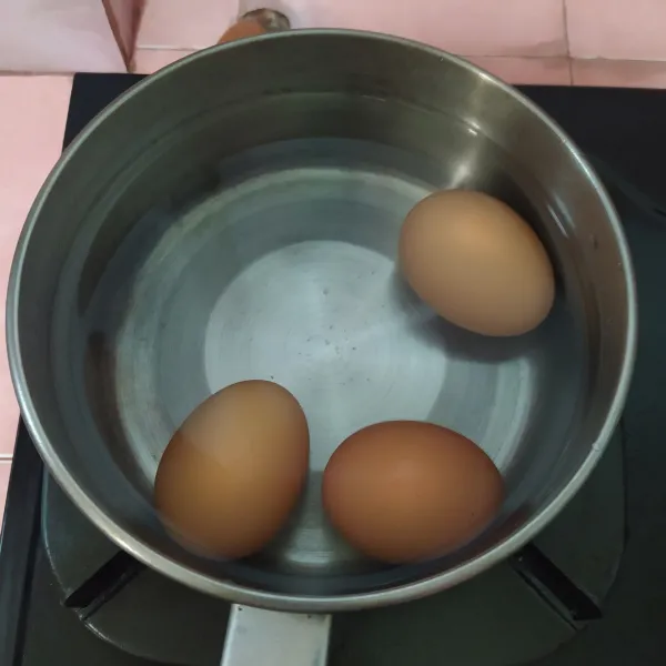 Didihkan air setinggi telur, tambah garam dan cuka. Kalau air sudah mendidih, masukan telur dengan sendok sayur, pelan-pelan saja agar tidak pecah, aduk telur perlahan searah jarum jam, agar nanti pas dibelah, kuning telur tepat berada di tengah. Rebus sesuai tingkat kematangan telur yang dimau (saya 7 menit dengan api kecil). Angkat, rendam di air es 10 menit atau di air yang mengalir lalu kupas.