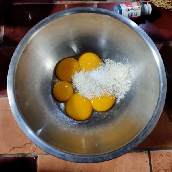 Kocok telur, gula pasir, dan vanila bubuk hingga gula larut dan berwarna pucat dengan menggunakan whisk.