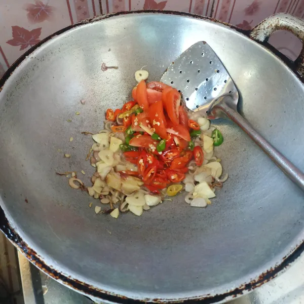 Selanjutnya masukkan cabai dan tomat, kemudian tumis hingga layu.
