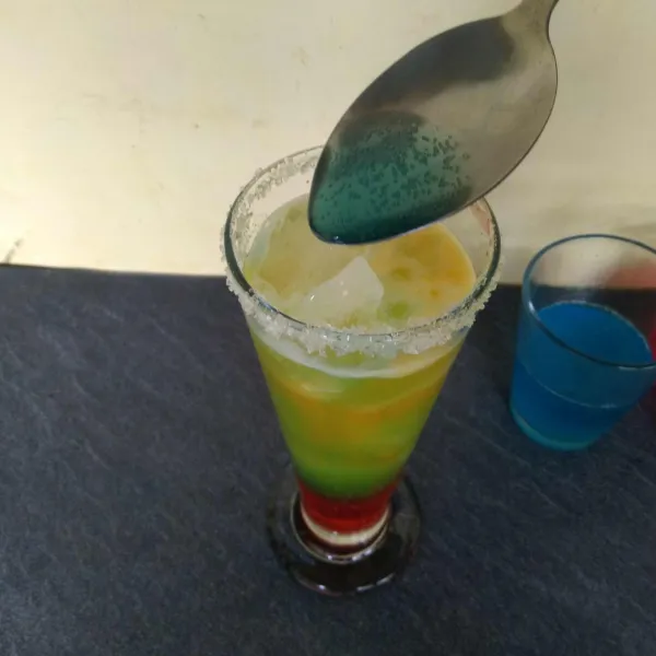 Tuangkan soda biru ke dalam gelas secara perlahan menggunakan sendok sampai gelas penuh. Sajikan. Aduk sebentar sebelum diminum.