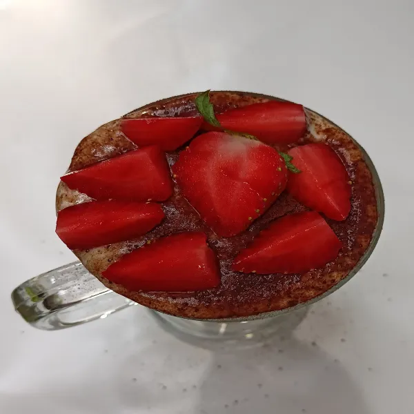 Tabur cocoa powder. Beri potongan strawberry.