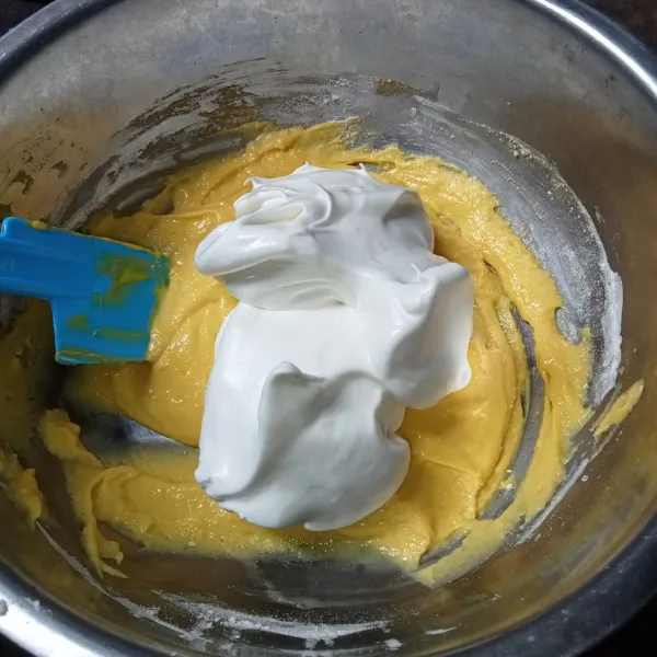 Lalu masukkan 1/3 adonan putih telur ke dalam adonan kuning telur dan aduk balik secara perlahan hingga tercampur rata.