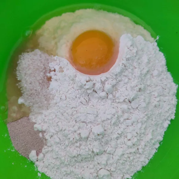 Pertama masukkan ke dalam wadah tepung terigu, gula, ragi instan, dan telur. Lalu tambahkan air sedikit demi sedikit sampai membentuk adonan.