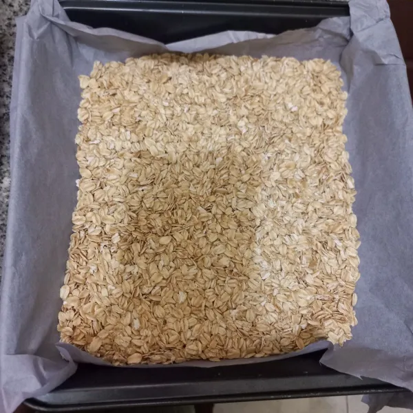 Siapkan loyang yang telah dialasi kertas roti  tuang rolled oats ke atasnya, panggang oats selama 15 menit sambil sesekali di aduk