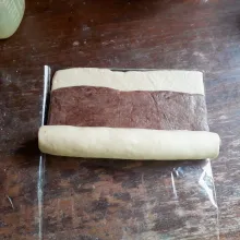 Olesi adonan putih dengan air, tumpuk dengan adonan coklat, olesi dengan air adonan coklat. Gulung dan rekatkan. Bungkus dengan plastik, simpan dalam freezer selama 45 menit.