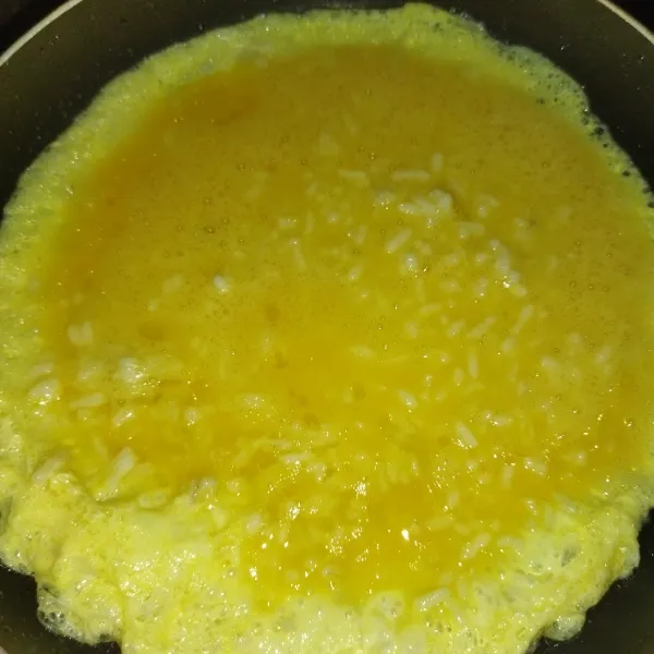 Panaskan minyak goreng, lalu tuang adonan omlet nasi, masak dengan api kecil.