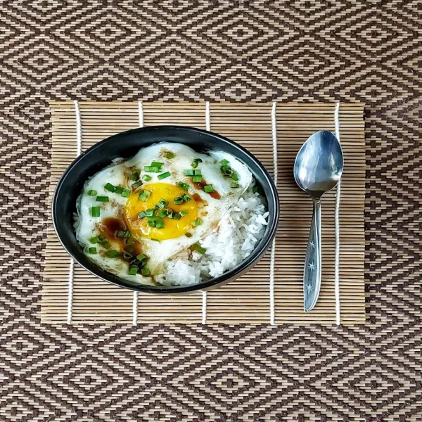 Letakkan telur diatas nasi . Siram dengan kecap asin dan minyak wijen. Taburi daun bawang.