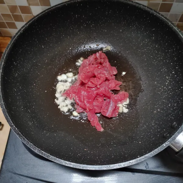 Panaskan minyak lalu tumis bawang putih hingga harum, kemudian masukkan daging sapi, aduk rata.