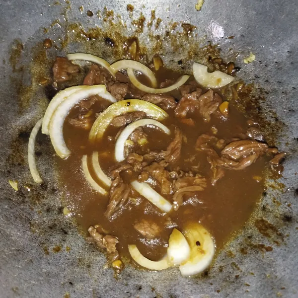 Aduk rata hingga daging berubah warna, lalu beri air dan masukkan bawang bombay, masak hingga daging sapi empuk.