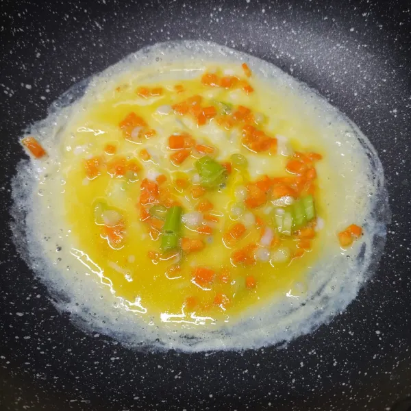 Panaskan pan anti lengket, oles sedikit minyak goreng. Tuang ½ bagian adonan telur, masak sampai berkulit bagian bawah.